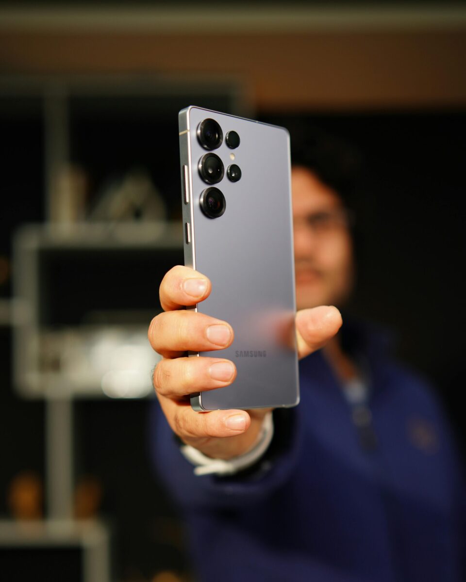 A person holding a Samsung smartphone with focus on the device, indoors.